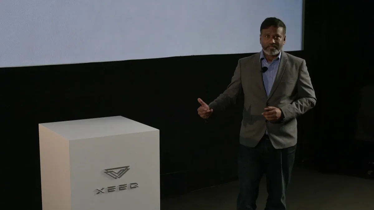 Dr. Gopi Balasubramanian presenting beside an XeedQ display